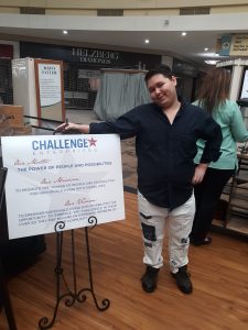 Person Standing next to Challenge Enterprises mission poster