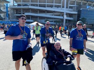 3 Runners talking a picture with a person with different abilities in a wheel chair